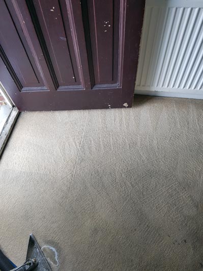 The same beige carpet by the doorway after professional cleaning